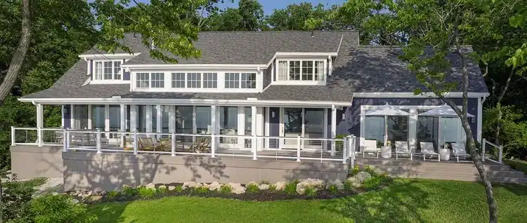 A home showcasing TimberTech Advanced PVC Decking in the Vintage Collection in the color Coastline. The deck railing features Horizontal Cable Infill with Drink Rail, a popular TimberTech composite railing choice.