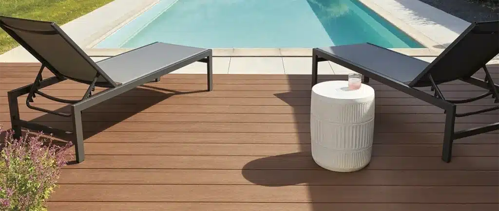 Mahogany colored pool deck sits at the edge of an in-ground pool