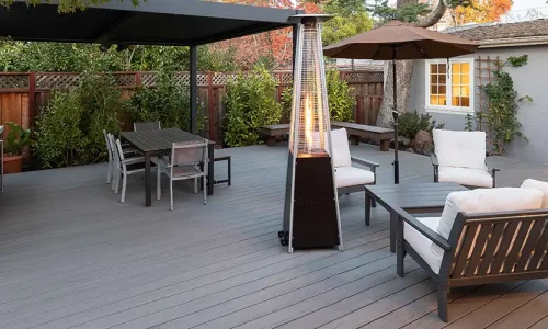 Outdoor deck in the shade at sunset with a heat lamp near two outdoor seating areas.