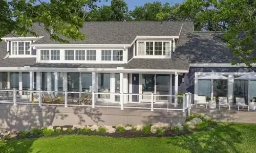 A home showcasing TimberTech Advanced PVC Decking in the Vintage Collection in the color Coastline. The deck railing features Horizontal Cable Infill with Drink Rail, a popular TimberTech composite railing choice.